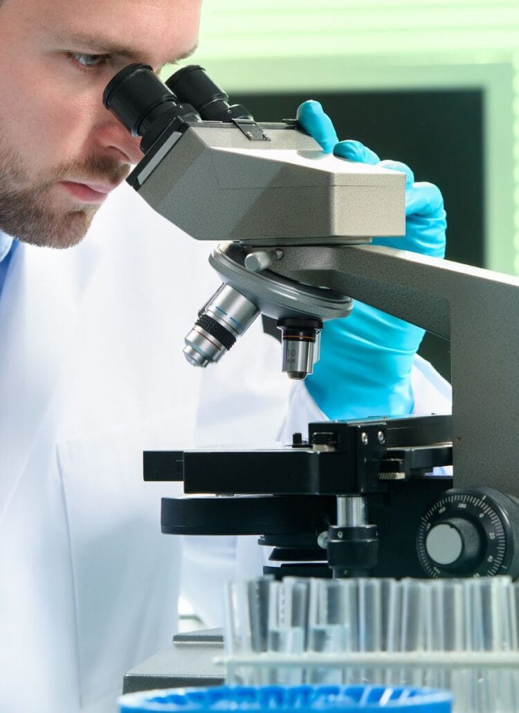 Pathologist diagnosing disease by looking through the microscope in the lab