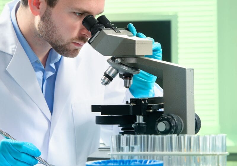 Pathologist diagnosing disease by looking through the microscope in the lab
