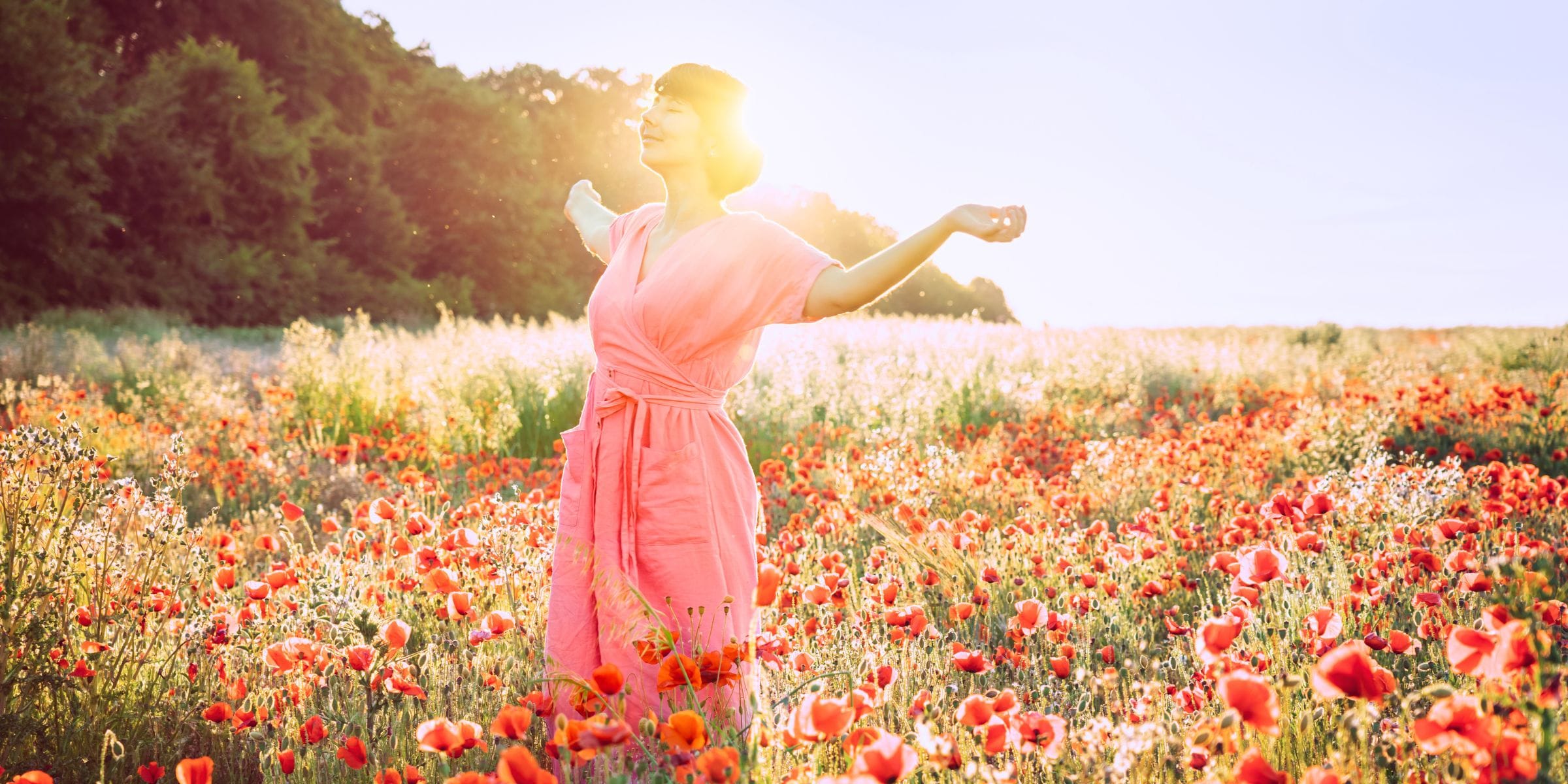 happy woman standing in a field of poppy flowers glowing