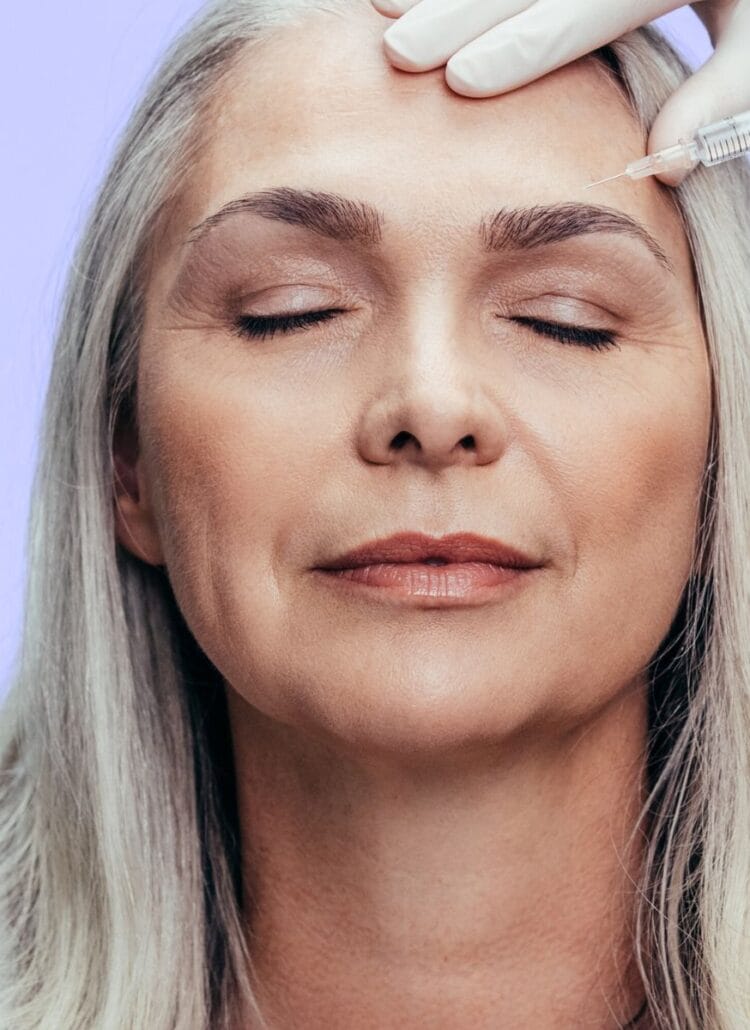 older woman receiving botox treatment to eyebrow wrinkles in forehead