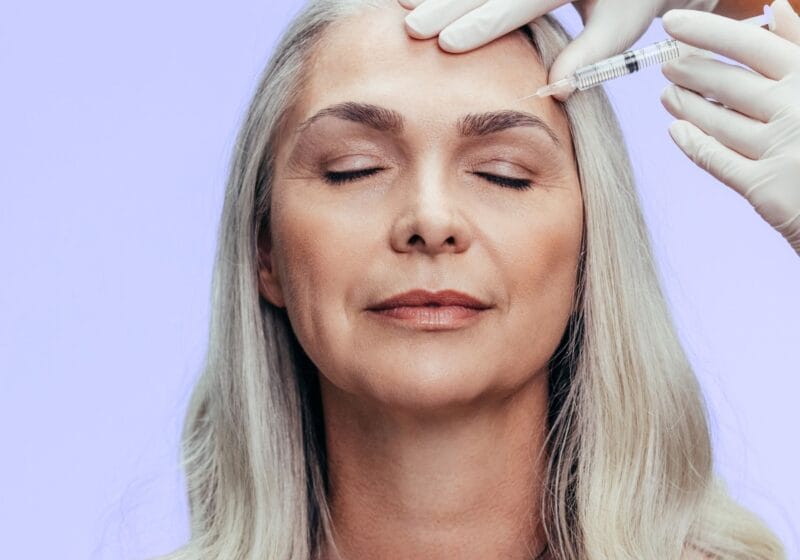 older woman receiving botox treatment to eyebrow wrinkles in forehead