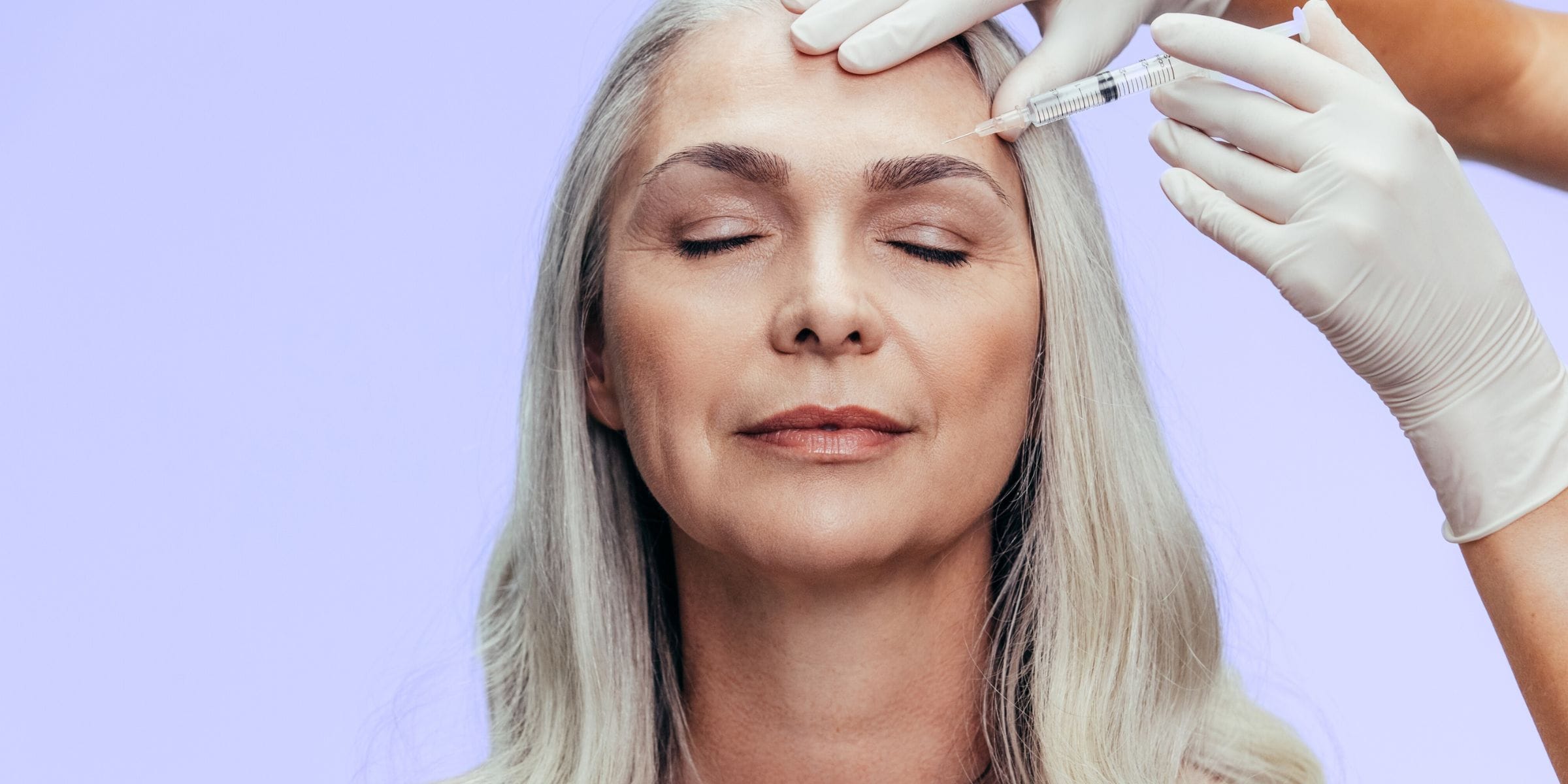 older woman receiving botox treatment to eyebrow wrinkles in forehead