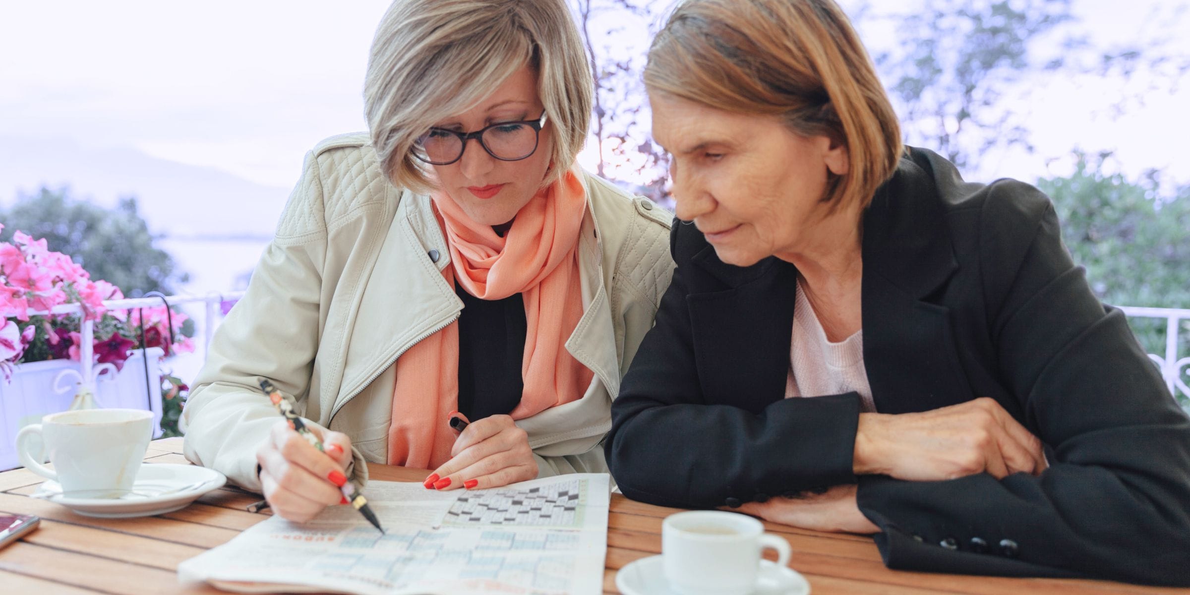 women relaxing together outdoors doing a puzzle book over tea