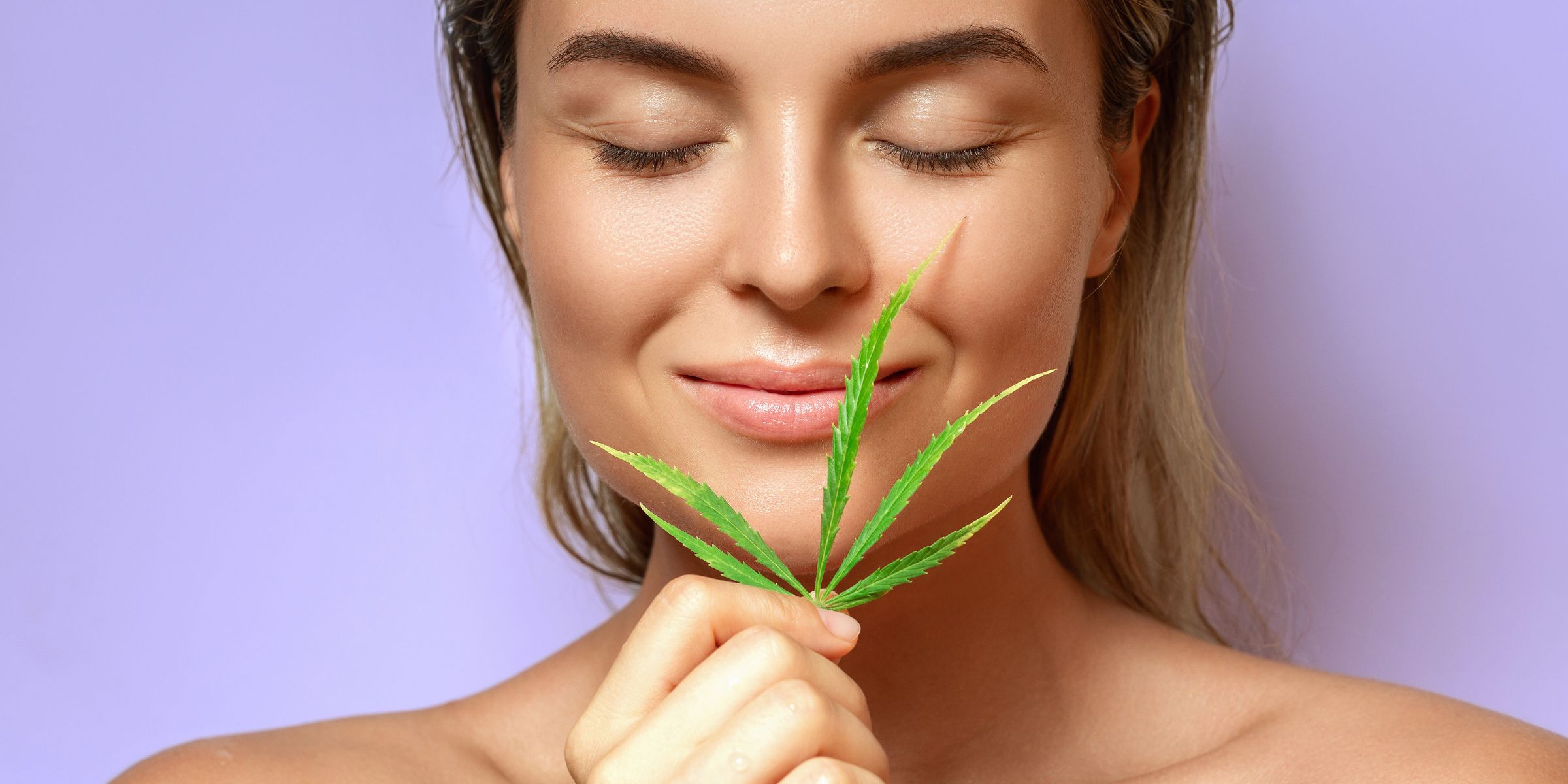 woman standing with hemp leaf smiling against purple background relaxed