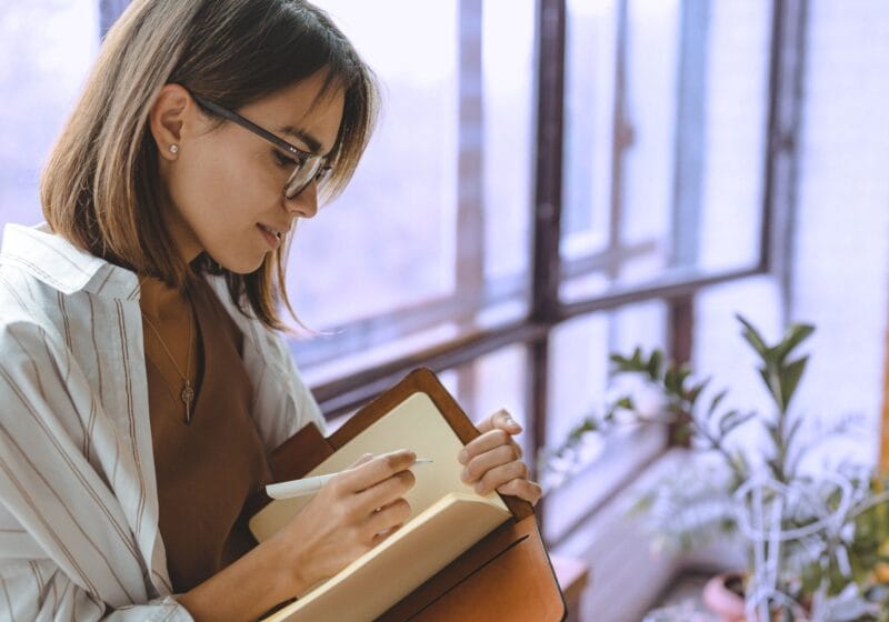 woman writing in her journal and reinforcing healthy habits