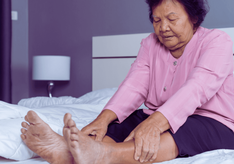 old asian woman in pink shirt in pain from venous insufficiency