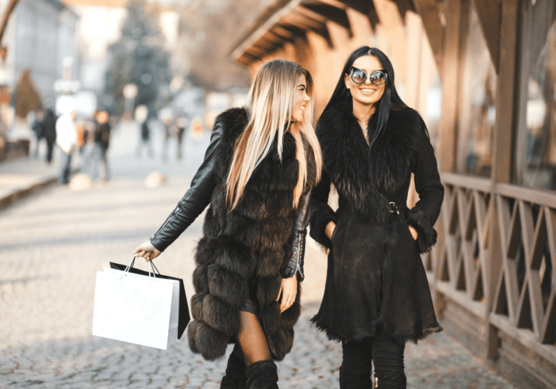 young women black furry coats in spain shopping