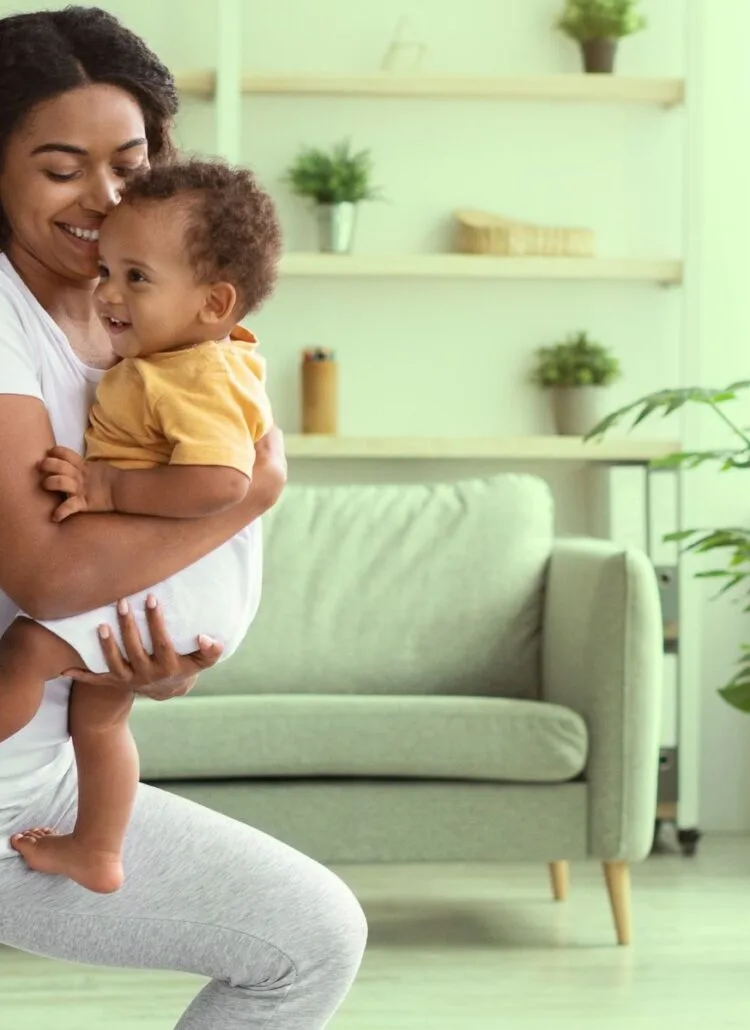 postpartum woman exercising holding her newborn baby