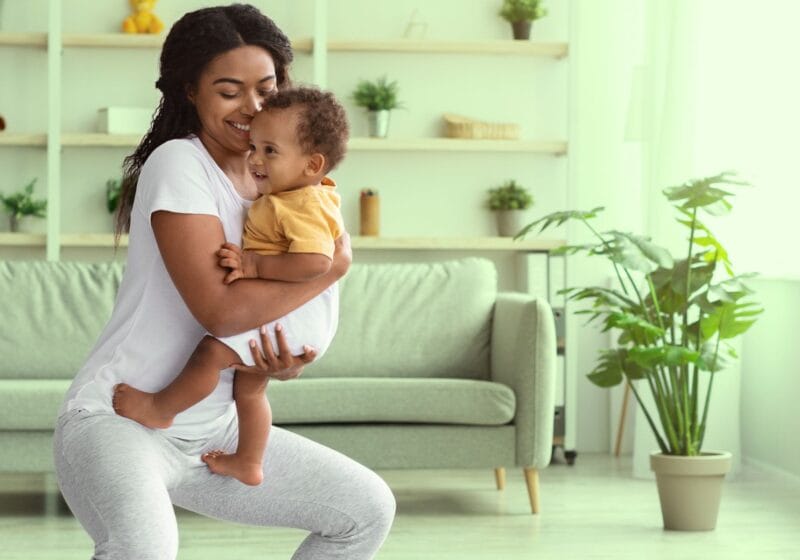 postpartum woman exercising holding her newborn baby