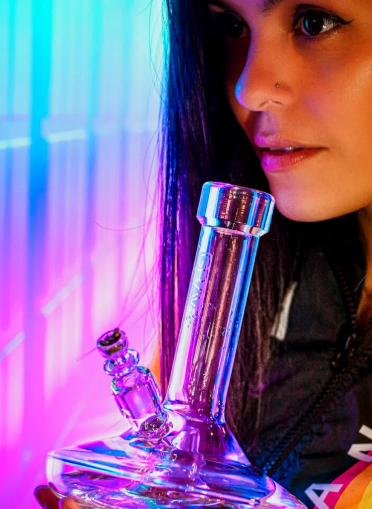 Young woman smoking marijuana out of glass bong