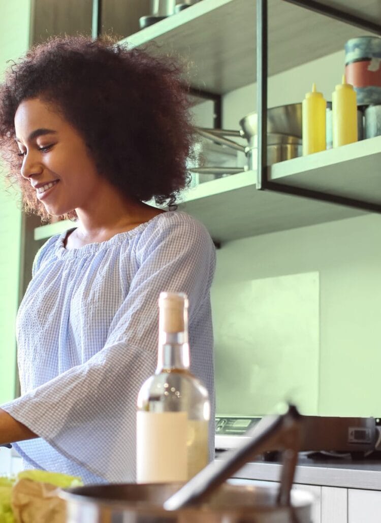 Woman making a healthy salad full of fiber for gut health in her kitchen