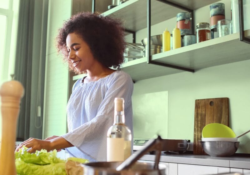 Woman making a healthy salad full of fiber for gut health in her kitchen