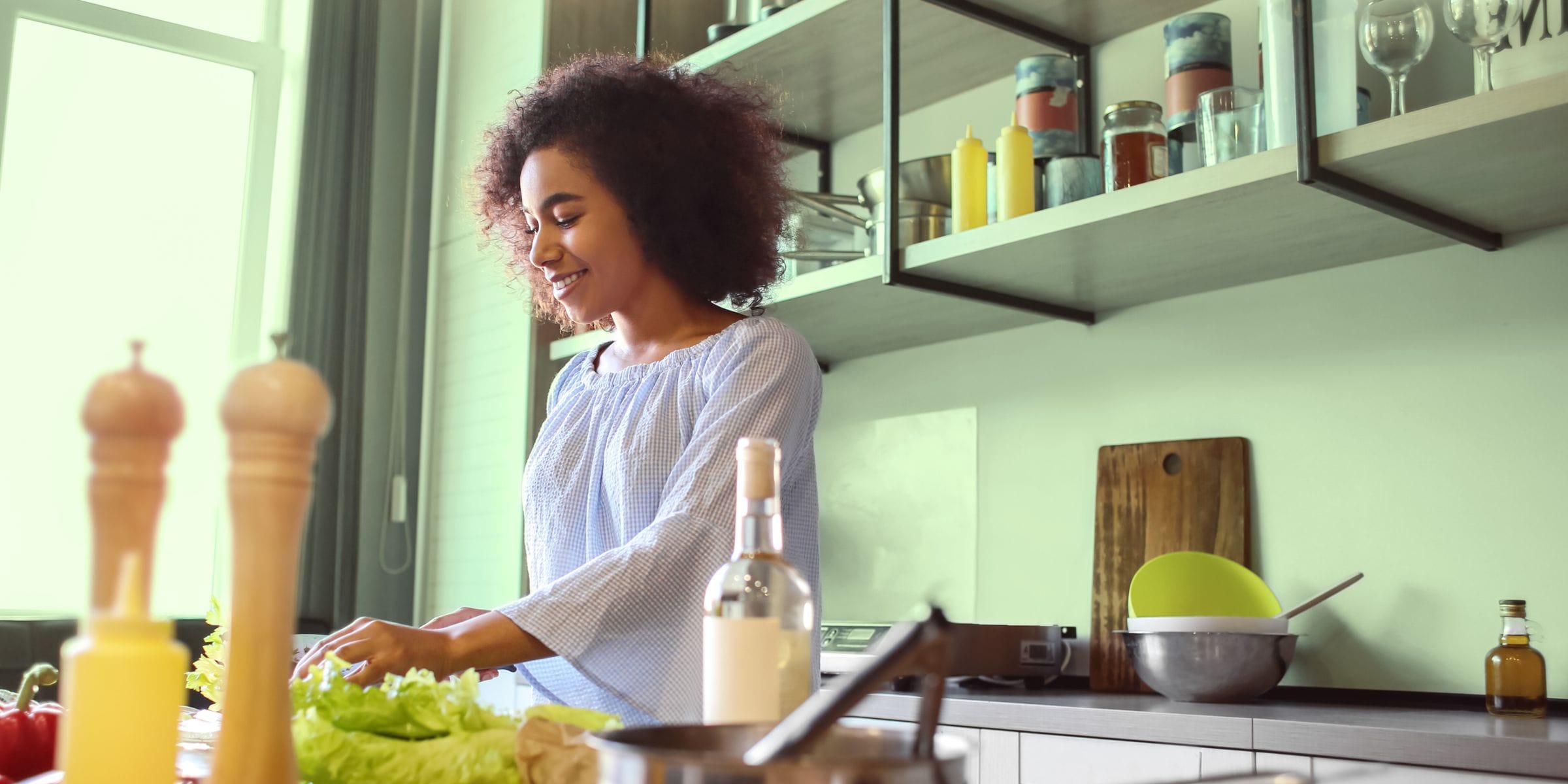 Woman making a healthy salad full of fiber for gut health in her kitchen