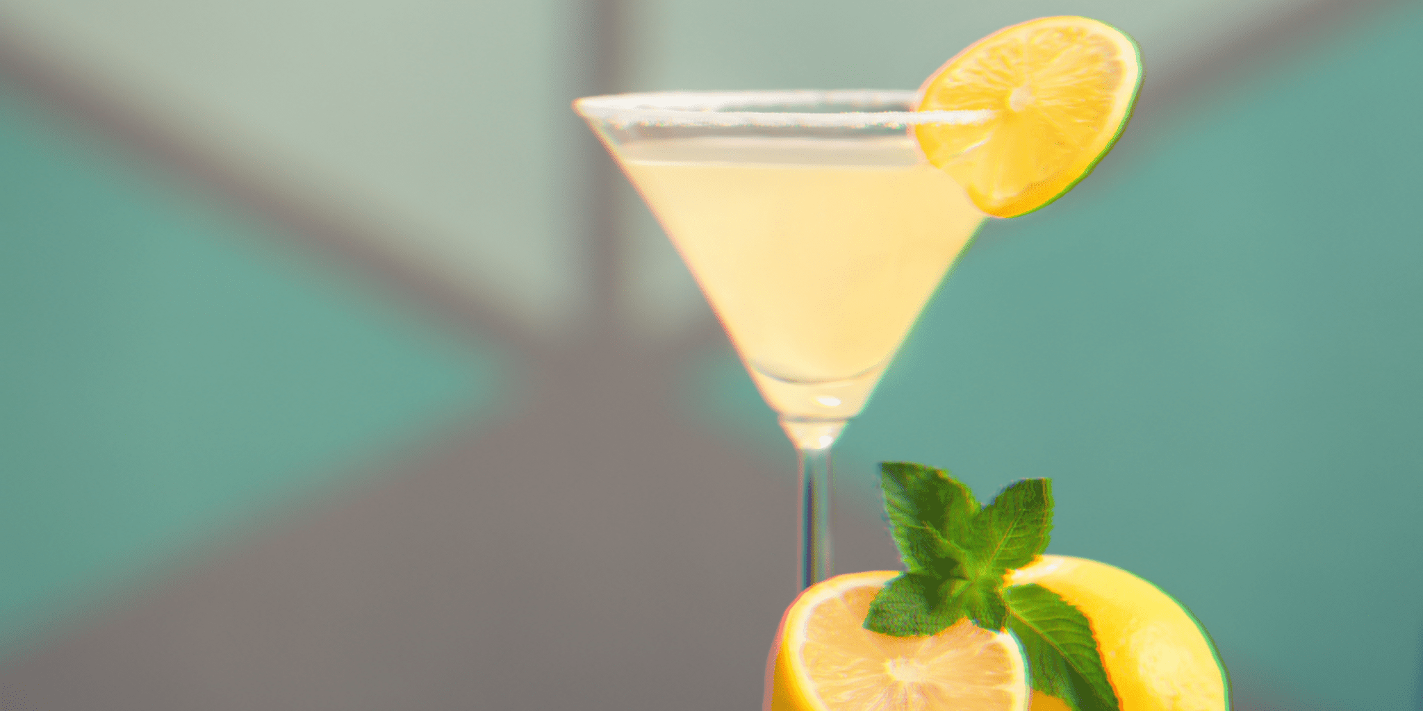 citrus lemon drop vodka drink in martini glass against blue wall with retro wallpaper