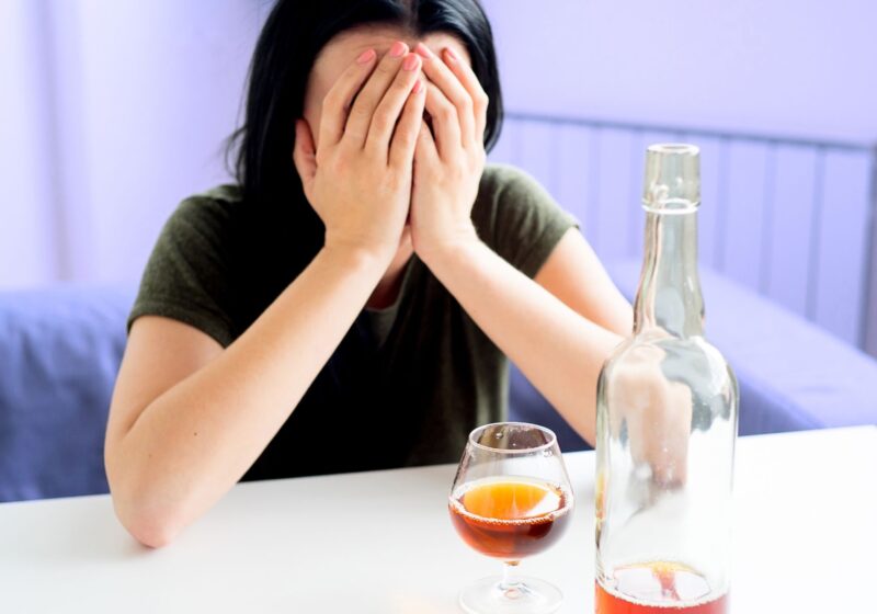 asian woman drinking a bottle of whiskey alone realizing she is an alcoholic