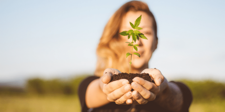 woman holding a baby cannabis plant in her 