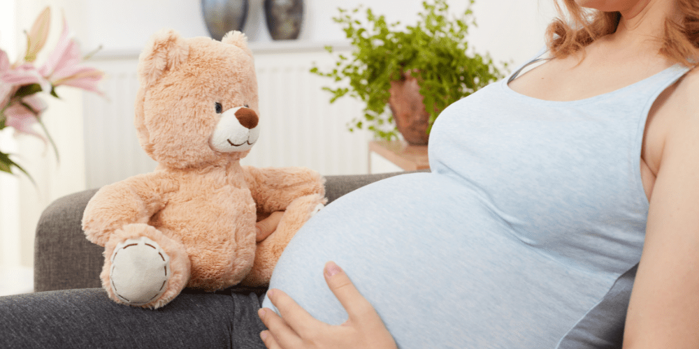 pregnant woman with teddy bear holding baby in belly