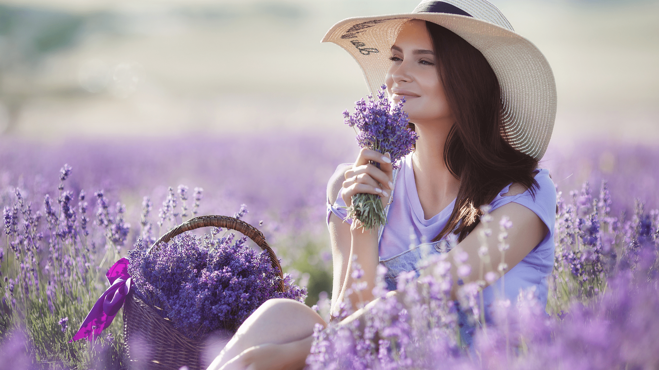 woman with hat on in in lavender field smelling the terpenes in the flowers