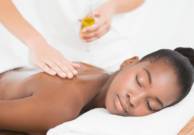 young black woman getting massage oil poured on her