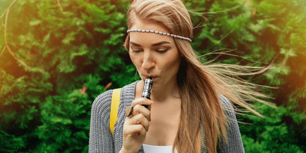 young woman vaping weed outside